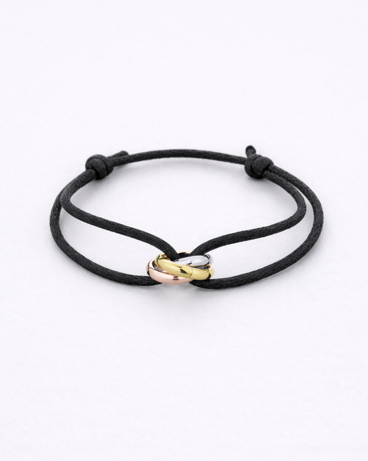 Black cord bracelet with gold and rose gold heart-shaped clasps on a white background