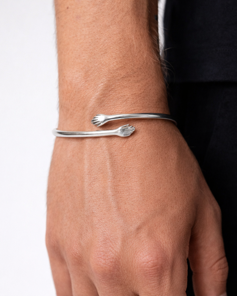 Silver bracelet on a wrist with a plain background